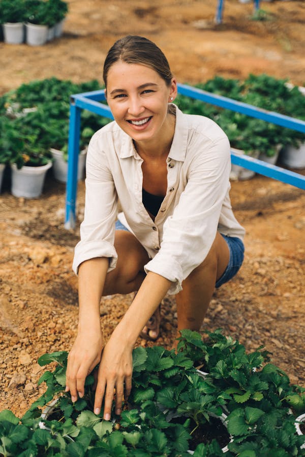 Smiling Woman Seated beside a Green Leaf Plant